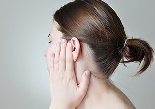 귀와 뺨 부위를 손으로 감싸고 통증을 호소하는 여성