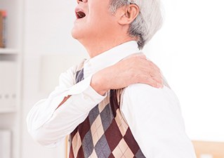 어깨를 짚으며 통증을 호소하는 고령 남성