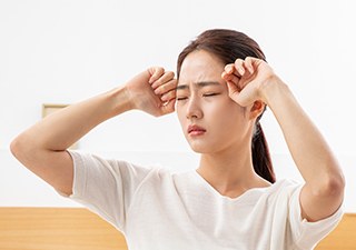 눈을 비비며 어지러움을 호소하는 여성