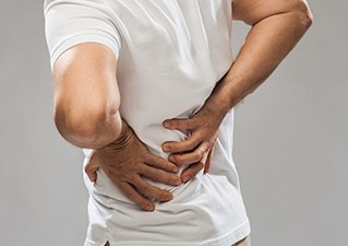 허리를 두 손으로 짚고 통증을 호소하는 모습
