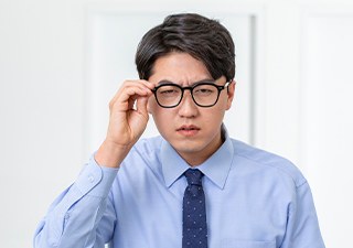안경을 고쳐 쓰며 시야 이상을 확인하는 남성